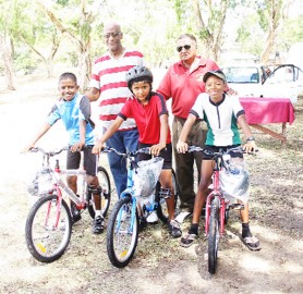 Nicholas Nandan, Deeraj Garbaran and Christopher Griffith pose with National Cycling Coach Hassan Mohammed and their new bikes. (Aubrey Crawford photo)