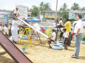 Deputy Country Representative of UNICEF, Rudi Luchmann (right) looks on as Head of Child Protection Services, Doris Roos (left), president of the SFCD, Alex Foster and Sharon Patterson of the ILO (second and third, right) assist the children at the play park at Eversham.
