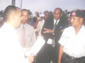 NFMU head Valmikki Singh (left) serves the warrant on Mark Benschop (second from left) yesterday as his attorney Nigel Hughes makes a point.  