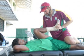 West Indies Physiotherapist Steve Forbes seeks to loosen up Guyana’s middle order batsman Narsingh Deonarine hamstring before his team’s net session yesterday. 