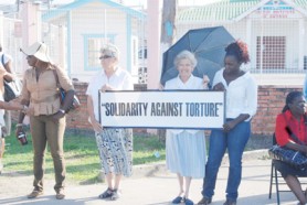 In solidarity: Participants at a vigil for the 15-year-old boy tortured by police while in their custody last week, hold a banner outside the Georgetown Public Hospital yesterday. 