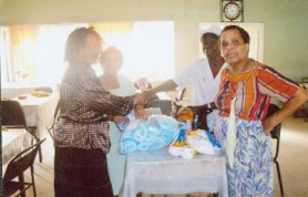 Nurse Bacchus (second right) and receives a donation for Uncle Eddie’s Home from Jacqueline Lamaison on behalf of He is the Way Ministries of Atlanta Georgia and Guyana. The items handed over included a quantity of toilet tissue, scrubs, latex gloves, adult pampers, disinfectant and detergent. Looking on are inmates of the home. 