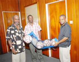 In this Aubrey Crawford photo, football promoter Lennox Arthur (left) receives a quantity of footballs from chairman of the Hope and Future - Guyana organization, Jocelyn Dolphin, while Terrence Haynes stands at centre displaying the other donated balls. 