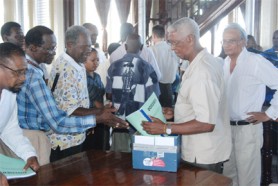 Some of those in attendance at City Hall yesterday for the launching of the joint opposition dossier, aimed at getting an international inquiry into human rights abuses here. Copies of the dossier were made available at the launch to organisations as well as members of the public. In the foreground is WPA Chairman Desmond Trotman (second from right) , who distributed copies while at extreme left is PNCR leader Robert Corbin and at extreme right is Dr Rupert Roopnaraine. (Jules Gibson photo) 