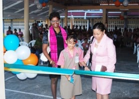 Minister within the Ministry of Education Dr Desrey Fox (right) and Country Director of Every Child Guyana Omattie Madray (left) look intently as essay competition winner Andrea Persaud cuts the ribbon officially opening the play park at the Eccles Primary yesterday afternoon. (Photo by Jules Gibson)