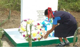 A student of the Port Kaituma Primary School places teddy bears at the memorial monument in memory of the children killed. (GINA photo)