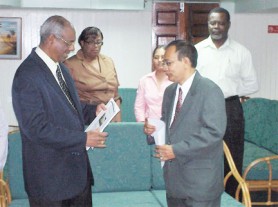 Speaker of the National Assembly Ralph Ramkarran (left) examines the report moments after receiving it from Acting Auditor General Deodat Sharma, while staffers of the Auditor General’s Office look on. 