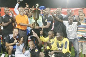 Super Champions! Prime Minister Samuel Hinds hands over the winning trophy to Alpha United’s captain Howard Lowe as the rest of team continues to celebrate their 2-1 win over GDF in the finals of the GFF Super League. (Orlando Charles photo)