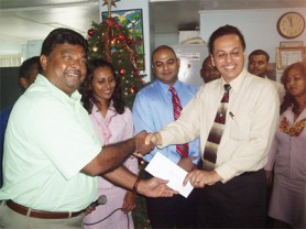 Fire Manager Director of Hand-in-Hand Fire Insurance, Howard Cox (right) hands over the cheque to Mokesh Daby.