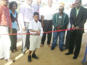Covent Garden Secondary School student Adian Rajkumar  is assisted by President Bharrat Jagdeo as he cuts the ribbon to officially open the new Diamond Well.