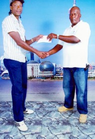 Randolph Roberts, right, coach of the Flying Ace Cycle Club, receives the sponsorship cheque from overseas-based Guyanese Franko Crawford.