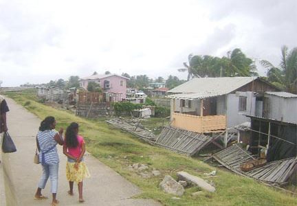 Two residents of Anna Catherina Sea View discuss their next move yesterday as they look at the remains of their home (extreme right). (Photo by Alva Solomon) 