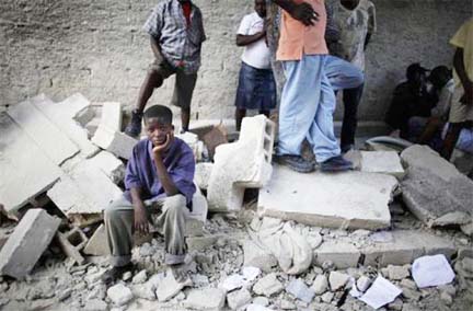 A boy sits next to the remains of a destroyed school after an earthquake in Port-au-Prince yesterday. REUTERS/Carlos Barria