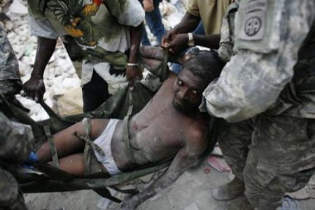 Rico Dibrivell, 35, is attended by a U.S. military rescue team after being freed from the rubble of a building in Port-au-Prince, January 26, 2010. REUTERS/Eduardo Munoz