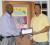 Co-Director of the K&S organization, Kashif Muhammad (right) receives a donation towards the HFF benefit match, from overseas-based Guyanese Mark Lee. (Aubrey Crawford Photo)