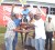 Mr. Peter Sangster (white T-shirt) of The PMTC presents the winning trophy to Chico Singh for winning the `I’ Division one and two events.