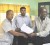 President of GAWU Komal Chand and Chairman of the NPC John Caesar shake hands after the signing of the agreement while Aslim Singh, Research Officer of GAWU looks on.