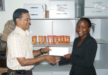 DDL’s Brand Executive, Alexis Crawford (right), hands over the sponsorship cheque to GCF’s Shiv Nandalall.