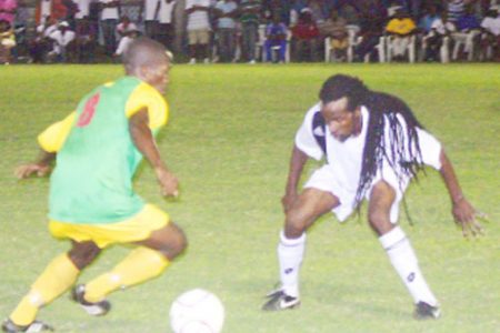 A Guyana Defence Force player tries some fancy footwork watched closely by a Santos defender. (Orlando Charles photo).