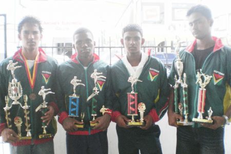 From left, Robert Pearson, Julian Amerally, Nicholas Kumar and Ganesh Babulall display the trophies they won in Trinidad. (Orlando Charles photo)