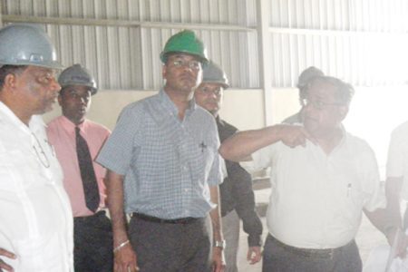 Sugar brief: Agriculture Minister, Robert Persaud (centre) listens as M.N Krishnamurthy, a sugar industry consultant from India, updates him on the Enmore packaging plant. Chairman of GuySuCo’s board, Dr. Nanda Gopaul (left) looks on in the company of other industry officials. 