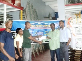 Supervisor of Star Party Rentals, Collin Archer presents the sponsorship cheque to boxer Clive Atwell (second right) while promoter Carwyn Holland (right) and staff members look on. 