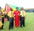Edmay Hendricks being escorted by some of her students, while others hold a Guyana flag behind her.
