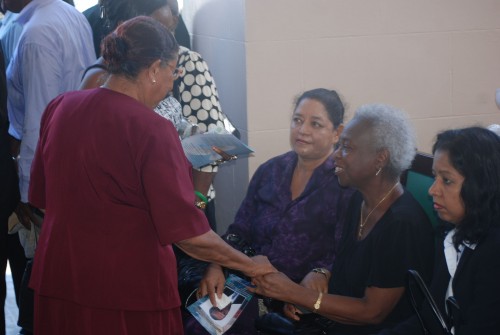 A mourner offers condolences to Winston Murray’s widow Marva (centre, seated) at Parliament Buildings today at the viewing of Murray’s body which lay in state from 10:00 hrs to 12:30 hrs. (Photo by Jules Gibson)
