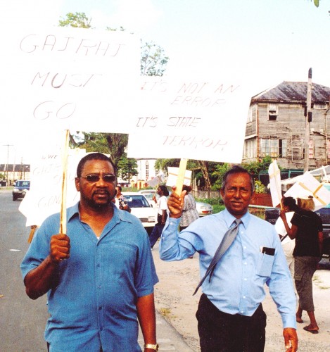 Winston Murray (right) protesting in January 2004 against Home Affairs Minister Ronald Gajraj who had been accused of associating with a death squad. His placard reads `It’s not an error. It’s state terror.’ At left is PNCR Leader Robert Corbin.