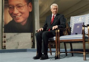 Chairman of the Norwegian Nobel Committee Thorbjoern Jagland looks down at the Nobel certificate and medal on the empty chair where this year's Nobel Peace Prize winner jailed Chinese dissident Liu Xiaobo would have sat, as a portrait of Liu is seen in the background, during the ceremony at Oslo City Hall today. REUTERS/Heiko Junge/Scanpix Norway/Pool
