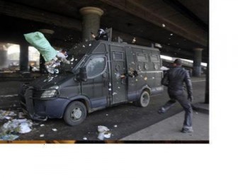 A protester runs next to a police vehicle after throwing a bag of trash at it during a demonstration in Cairo January 28, 2011.  REUTERS/Goran Tomasevic