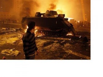 A protester looks at a burnt Egyptian Army armoured vehicle in downtown Cairo, January 28, 2011. REUTERS/Goran Tomasevic