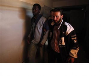 A suspected African mercenary (L) walks escorted by anti-government protesters as he is being held within a courthouse in Benghazi February 25, 2011. REUTERS/Suhaib Salem