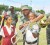 A member of the GDF Band Corps teaches an excited Number Eight Primary School student how to hold the trumpet while another student looks on.  