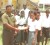 RHTYSC Assistant Secretary Narmala Sewdat hands over the billboard to Port Mourant Secondary School Senior Master Rohan Etwaru in the presence of some of students and another teacher.