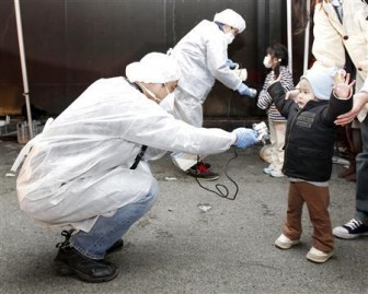 Officials in protective gear check for signs of radiation on children who are from the evacuation area near the Fukushima Daini nuclear plant in Koriyama, March 13, 2011. REUTERS/Kim Kyung-Hoon
