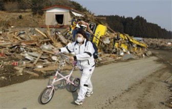 A woman pushes a bicycle as she walks through the rubble in Rikuzentakata, northern Japan after the magnitude 8.9 earthquake and tsunami struck the area, March 13, 2011. REUTERS/Lee Jae-Won