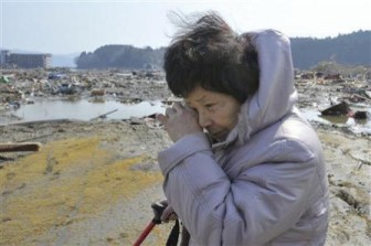 A woman searches for her missing husband amid debris after an earthquake and tsunami struck Minamisanriku, Miyagi Prefecture in northern Japan March 13, 2011. REUTERS/Kyodo