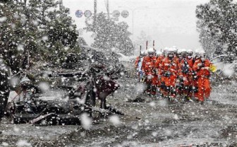 Heavy snow falls on rubble and rescue workers at a devastated factory area hit by an earthquake and tsunami in Sendai, northern Japan March 16, 2011. REUTERS/Kim Kyung-Hoon