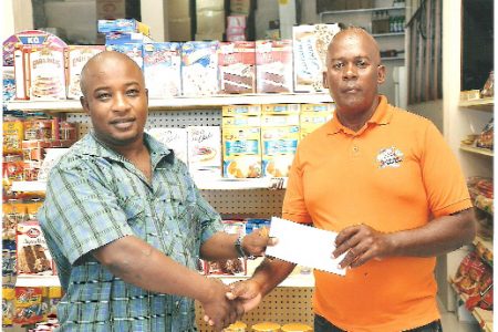 Chief Executive Officer of the Stretch D Dollar Rudolph Blair hands over the sponsorship cheque of an undisclosed sum to coach Randolph Roberts. 