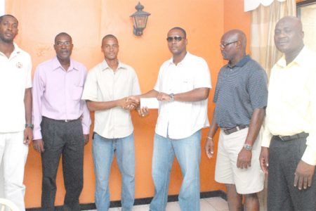 Carey Griffith (third from right) hands over the donation to Guyana’s captain Steve Neil Jr.