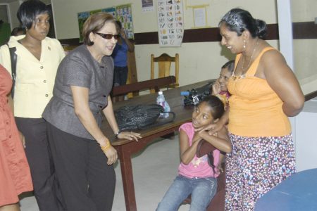 Prime Minister of Trinidad & Tobago, Kamla Persad-Bissessar  (second from left) takes time out to chat with a child at the GPHC where she had gone to visit with the passengers who were injured in Saturday morning’s crash-landing of BW 523. (Orlando Charles photo)