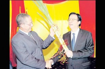 Prime Minister Bruce Golding (left) hands over sugar cane plants to Tang Jianguo, chief executive officer of the COMPLANT Group of Companies to symbolise the handover of Government-held sugar industry assets to the Chinese company during a ceremony at the Jamaica Pegasus hotel. (Jamaica Observer photo)