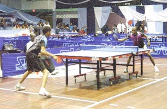 Nigel Bryan (far end of the table) stretches for another return during his semifinal match-up.(Orlando Charles photo)