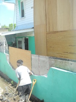 A relative of the Razzacks removing debris from the fence in preparation for work to be done tomorrow.