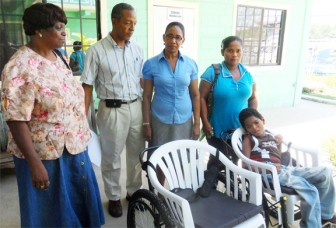 In the photo, Antone sits in his wheelchair as Dr. and Mrs. Haynes and others look on.  