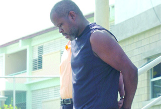 A handcuffed Selwyn "Robocop" Alexis leaves the Gasparillo Police Station on his way to the San Fernando Magistrates' Court yesterday on a charge of murder.  (Trinidad Express photo)