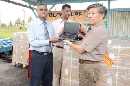 Labour Minister Manzoor Nadir (left) receives one of the just-arrived laptops from Brian James whose company, Auto Supplies, is the local dealer for the Haier brand computer. At centre is CEO of the OLPF project, Sesh Sukhdeo. (Photo by Anjuli Persaud)