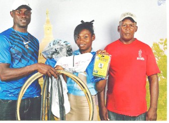Marica Dick, centre, receives the cycling equipment from Wilbert Benjamin, left, while her coach Randolph Roberts looks on.
