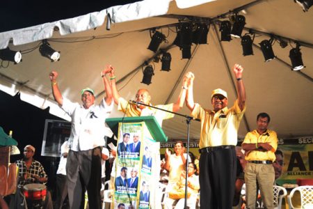 From left: Dr Richard Van West Charles, Raphael Trotman and Moses Nagamootoo in a joint wave to the crowd while presidential candidate Khemraj Ramjattan (right) and others look on at the Parade Ground last night
